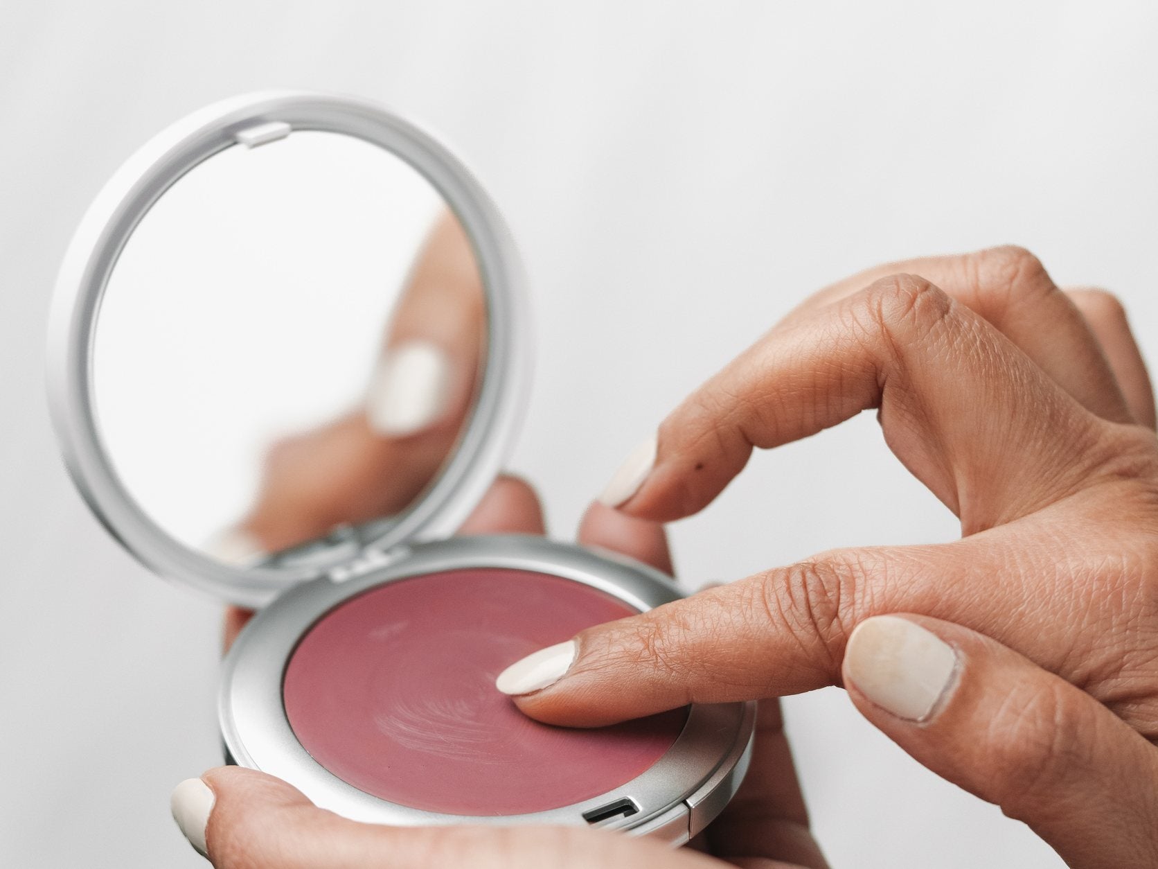 Hands pressing a fingertip into Haute Flash cream color with the mirror lid open, t3