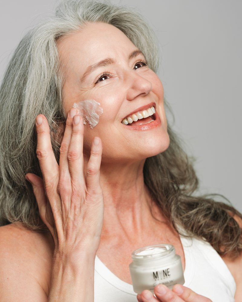 Woman smoothing Sleep With Me night cream onto her cheek, t1