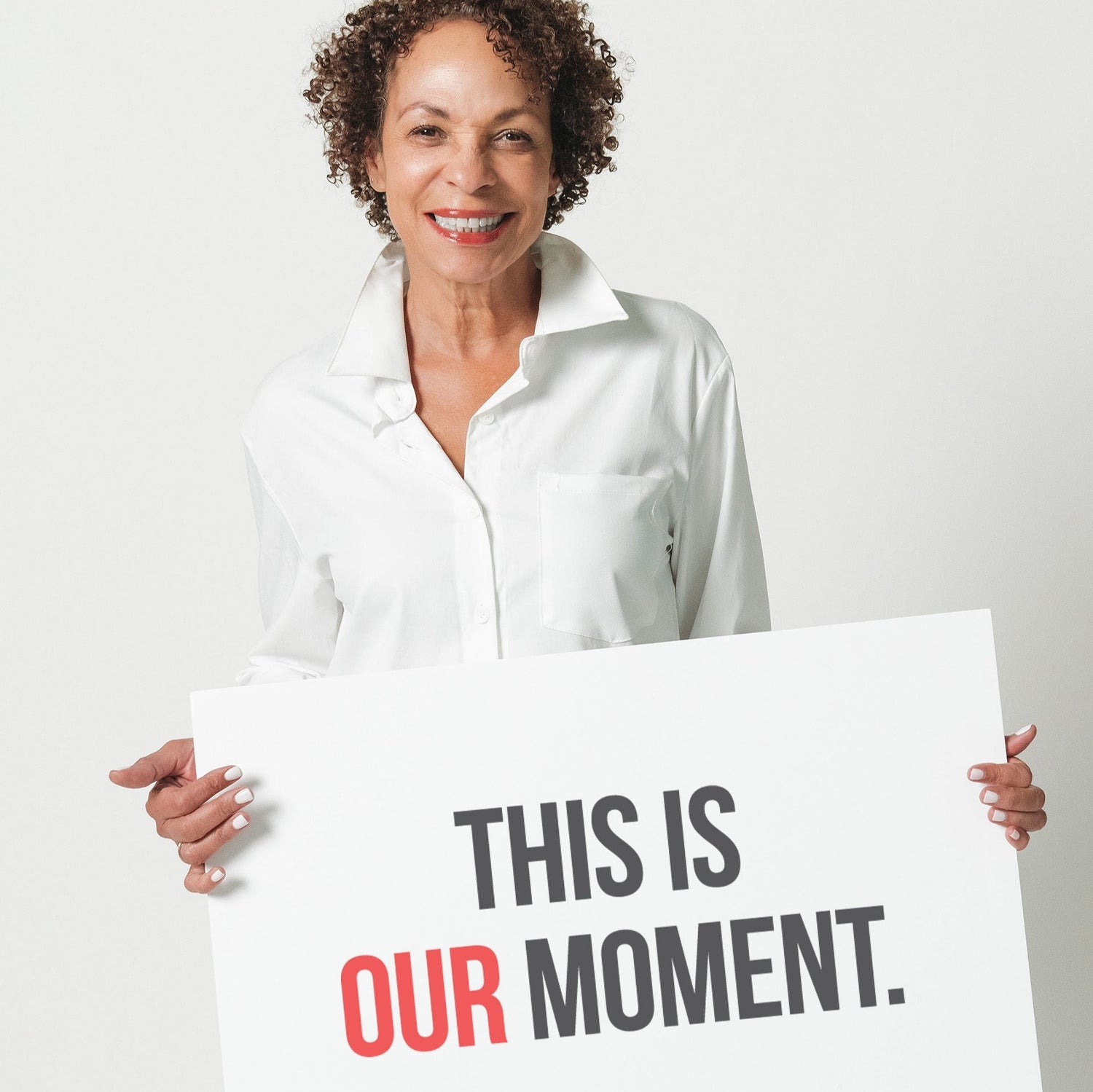 A woman in a white shirt holding a sign that says "This is our moment."