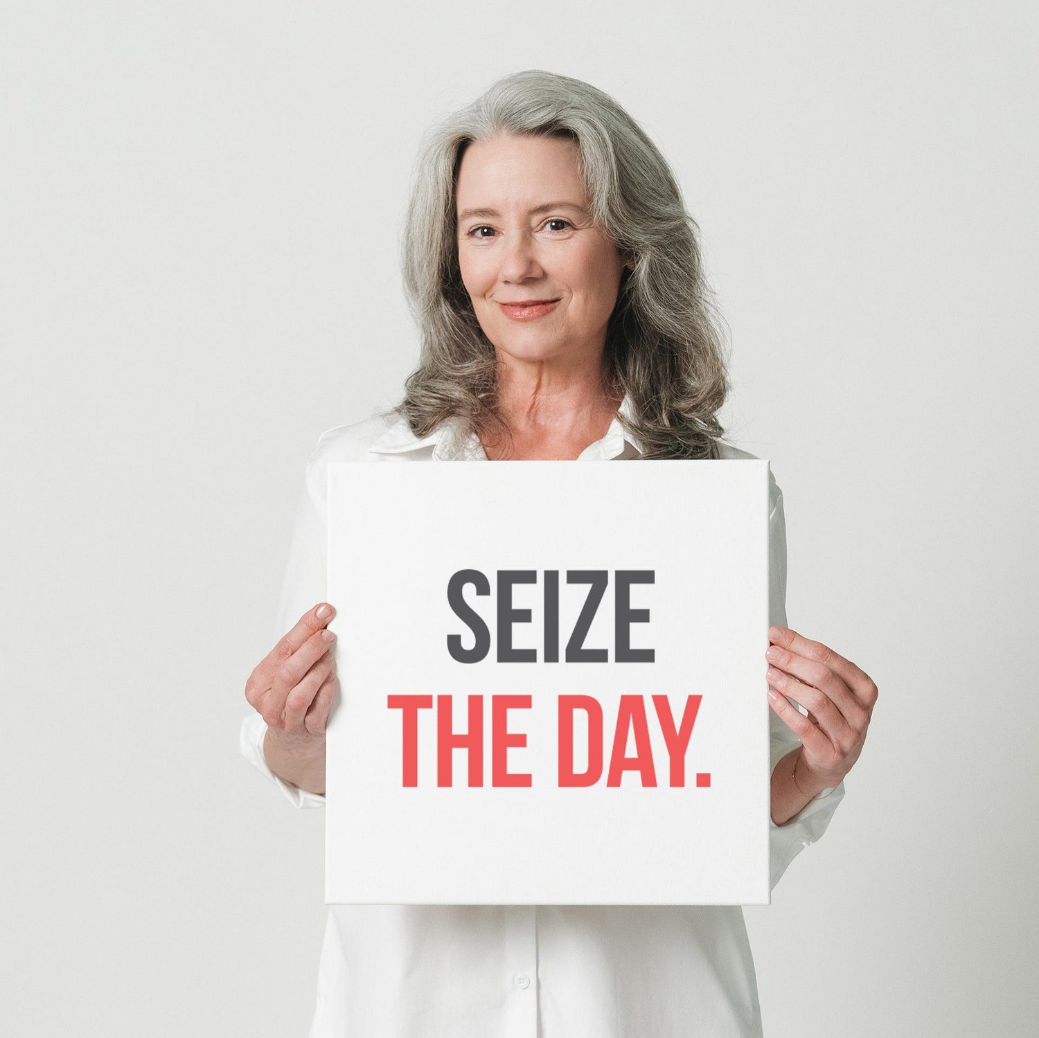 A woman in a white shirt holding a small sign that says "Seize the day"