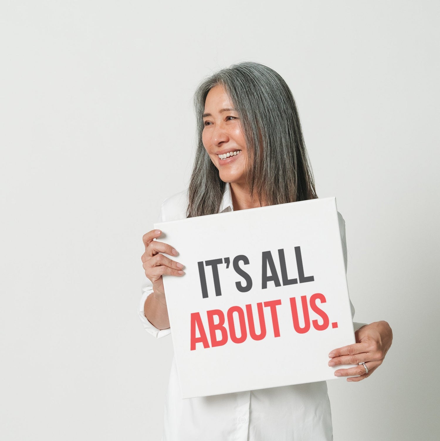 A woman holding a sign that reads "it's all about us."