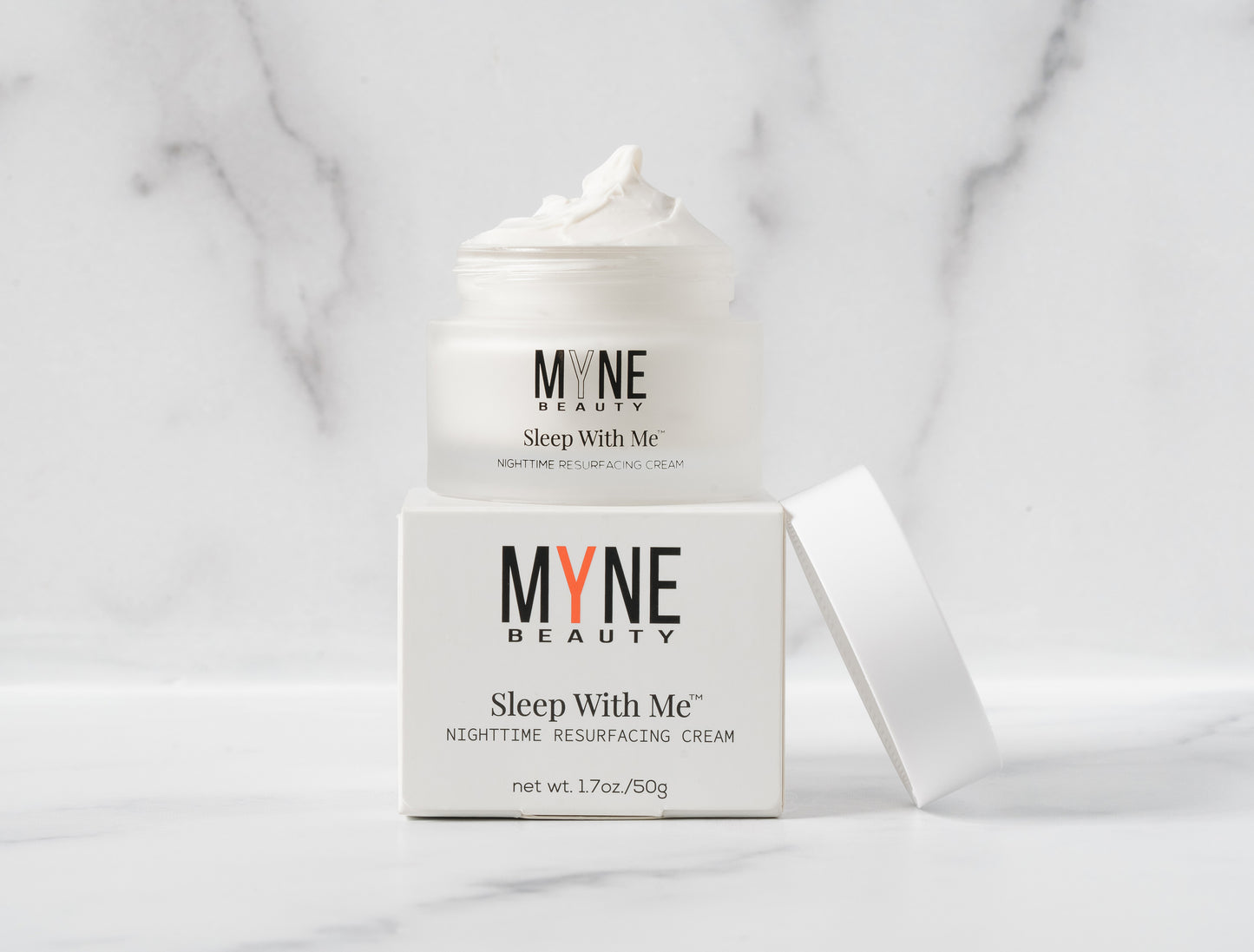 A jar of Sleep With Me Nighttime Resurfacing Cream with the lid off, sitting on its packaging box. Both the jar and the box have the Myne Beauty logo on them.