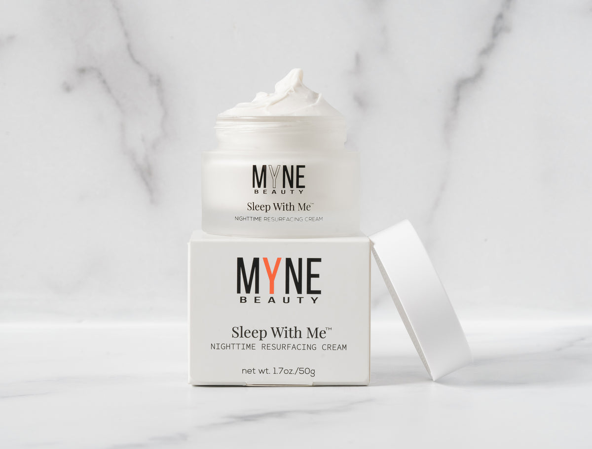 A jar of Sleep With Me Nighttime Resurfacing Cream with the lid off, sitting on its packaging box. Both the jar and the box have the Myne Beauty logo on them., t4