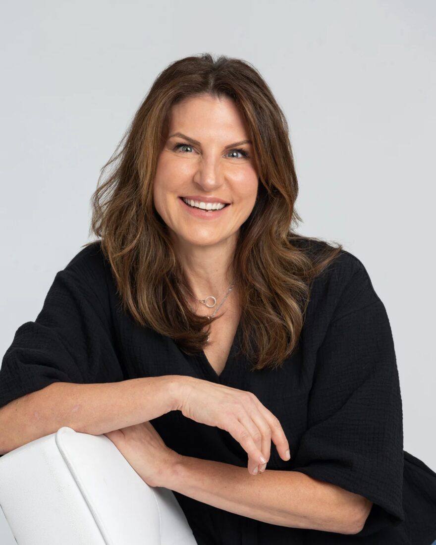 Liz Martin, founder of MYNE Beauty, in a black top on a white chair, t5